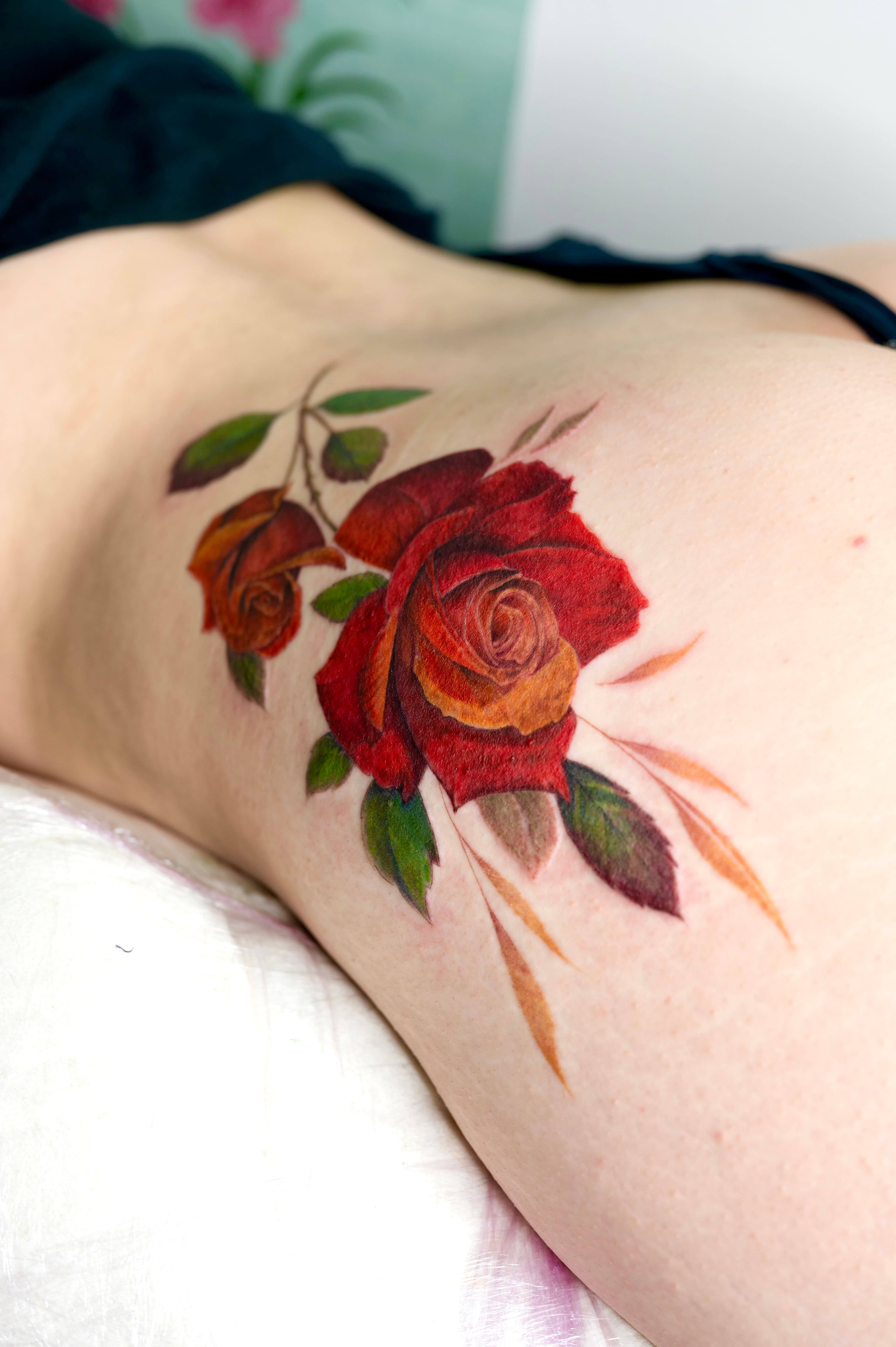 Tatouage fleurs couchées en couleur réalisé par Bertille Noblecourt